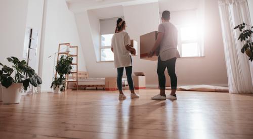 Couple in new house in the suburbs holding moving boxes