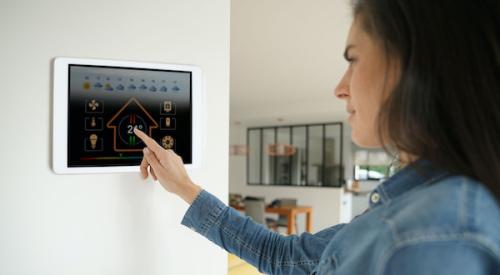 Woman using smart home touch screen on wall