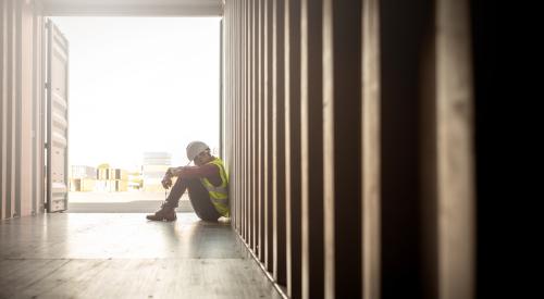 Construction worker sitting with head down