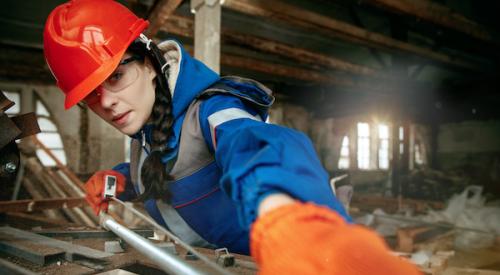 Woman measuring pieces of lumber on a construction site