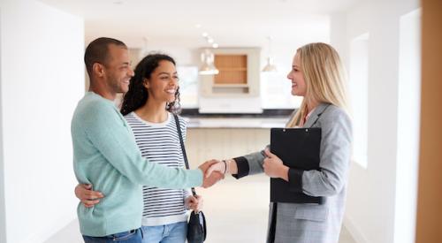 Smiling couple shakes hands with realtor inside a home