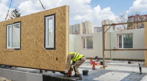 Builder placing prefab home wall