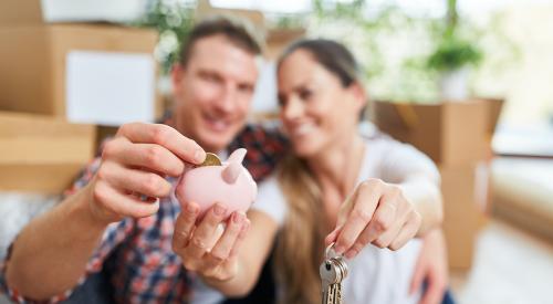 Homeowners smiling and putting coin into piggy bank