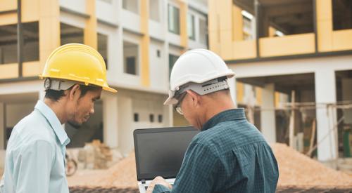Two construction workers using a laptop 