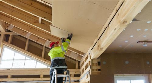 Home builder adding insulation to ceiling of home