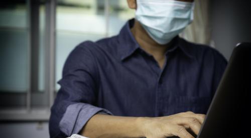 Man working at laptop with mask