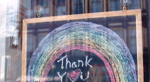 A chalkboard sign saying 'Thank you essential workers' hanging in a window