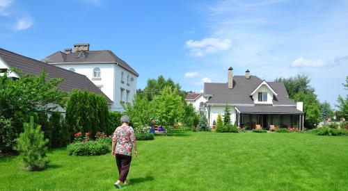 Older homebuyer walks through yard to small home