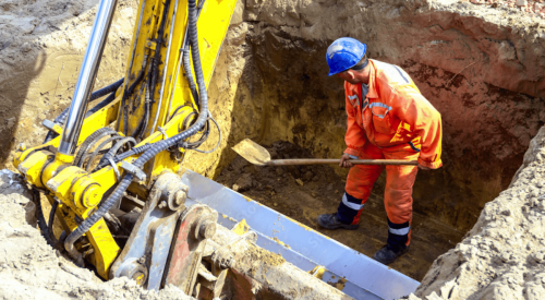 Construction worker digging a trench on a construction jobsite 
