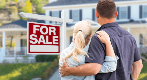 Couple standing together next to for-sale sign looking at home