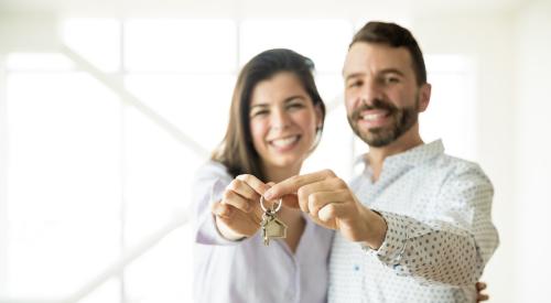 A man and woman hold up a set of keys.