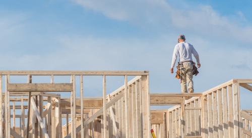 Builder walking on house frame