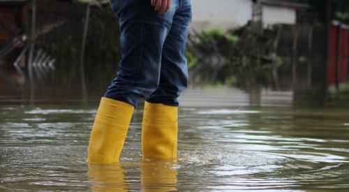Person wearing yellow boots wading through flood waters