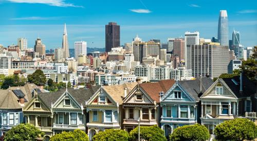 Row of colorful houses backdropped by San Francisco skyline