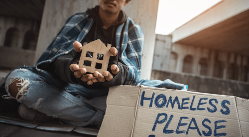 Seated homeless man with 'Please Help' cardboard sign