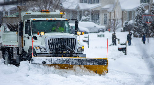 Snow plough clearing street in severe winter weather 