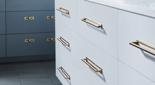Top Knobs' kitchen cabinet hardware in brass and gold tones on white and dark teal kitchen cabinets