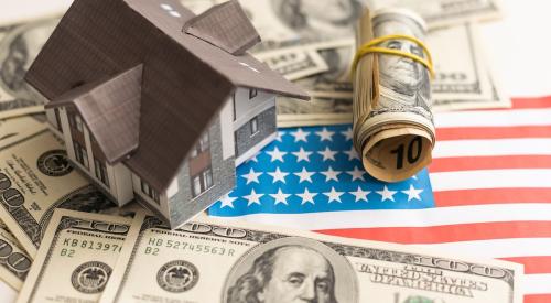 House model surrounded by cash on top of American flag cut out