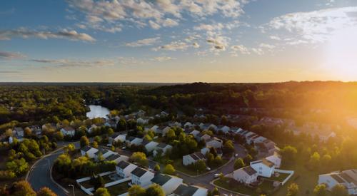 aerial view of homes in a neighborhood with sun rising over hill