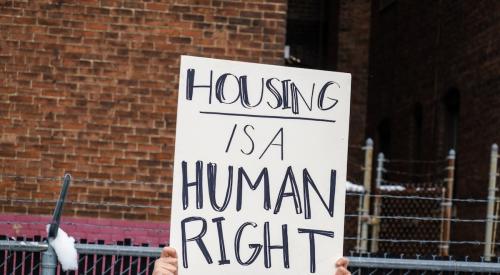Woman holding sign reading "housing is a human right"