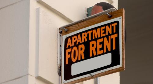 Apartment for rent sign with orange lettering on white building