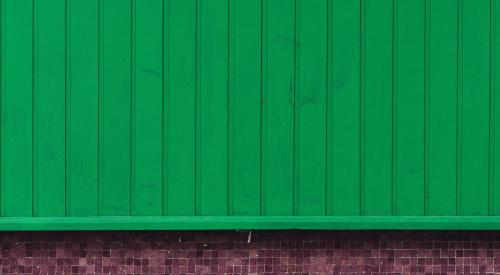 Green siding over brick wall