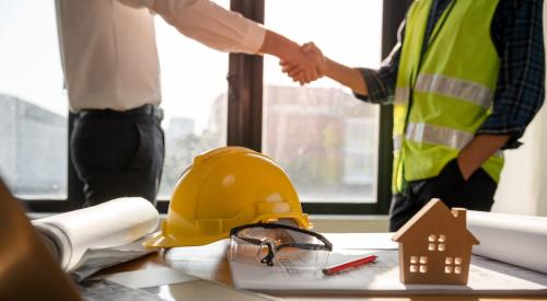 Builder shaking hands with businessman in front of office desk