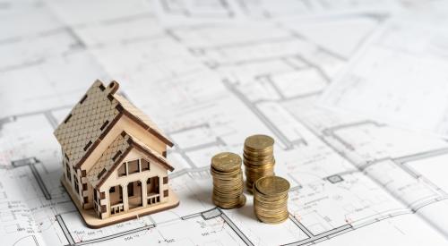 Small house model and stacks of coins on house plans