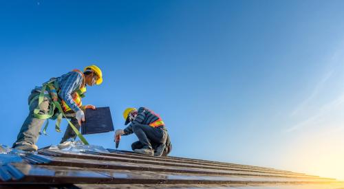 Construction workers installing roof tile