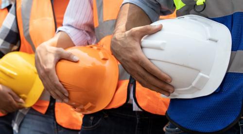 Construction workers standing in line holding hard hats