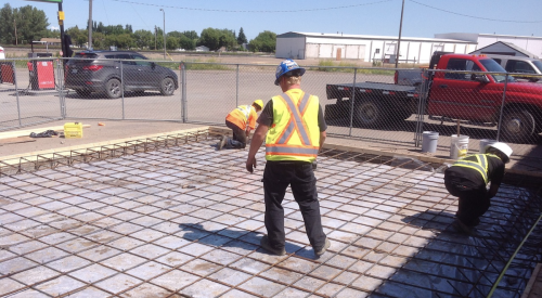Construction worker inspects concrete slab for new home construction