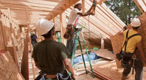 Construction workers framing house under construction