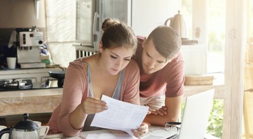 young couple looking over bills at kitchen table