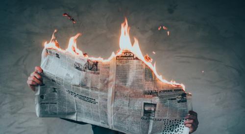 newspaper on fire while a man reads it