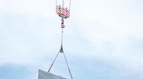 Prefab wall panel being lowered into place by a crane