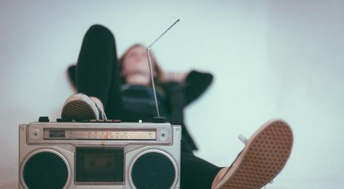 Person lying down with foot on retro boombox