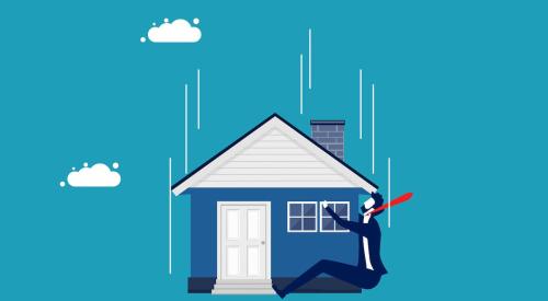 Businessman in suit holding onto falling house with blue background
