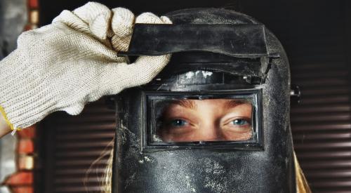 Young woman with blonde hair wearing welder mask