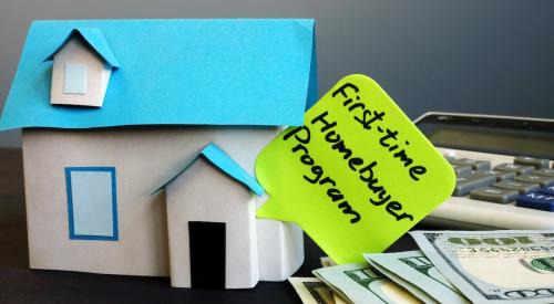 First time buyer program sticky note on house next to stack of money