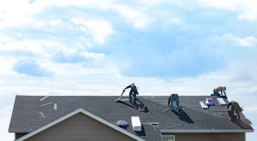 Construction workers repairing roof on old house