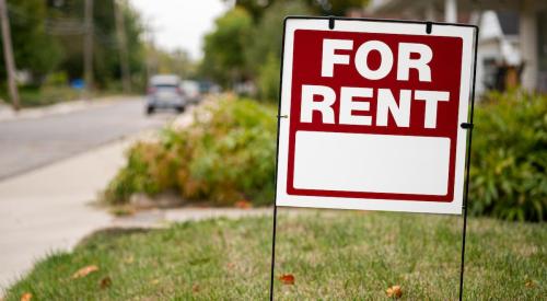 Red and white for-rent sign stuck in residential lawn in the suburbs