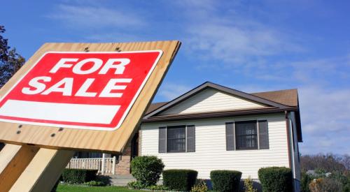 For sale sign falling on residential lawn outside of single-family home