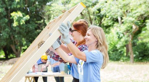 Girls raising wood-framed wall