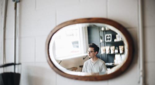 Young man in café as viewed through a mirror