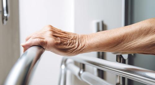 Elderly woman grabbing handrail in bathroom