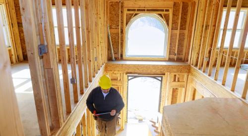 Home builder climbing stairs inside house under construction