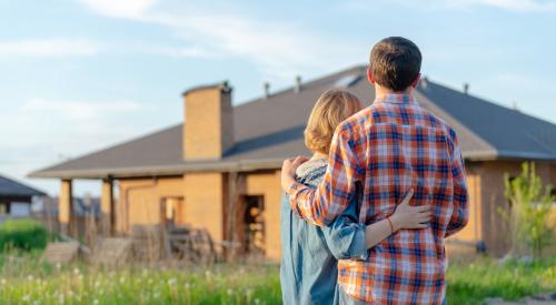 Homeowners hugging and standing outside of home