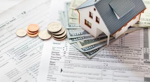Small house, stack of cash, and coins on top of tax forms