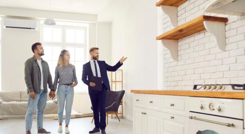 Realtor in kitchen taking young couple on open house tour
