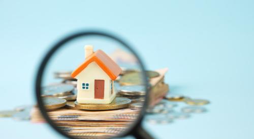 House on coins under magnifying glass